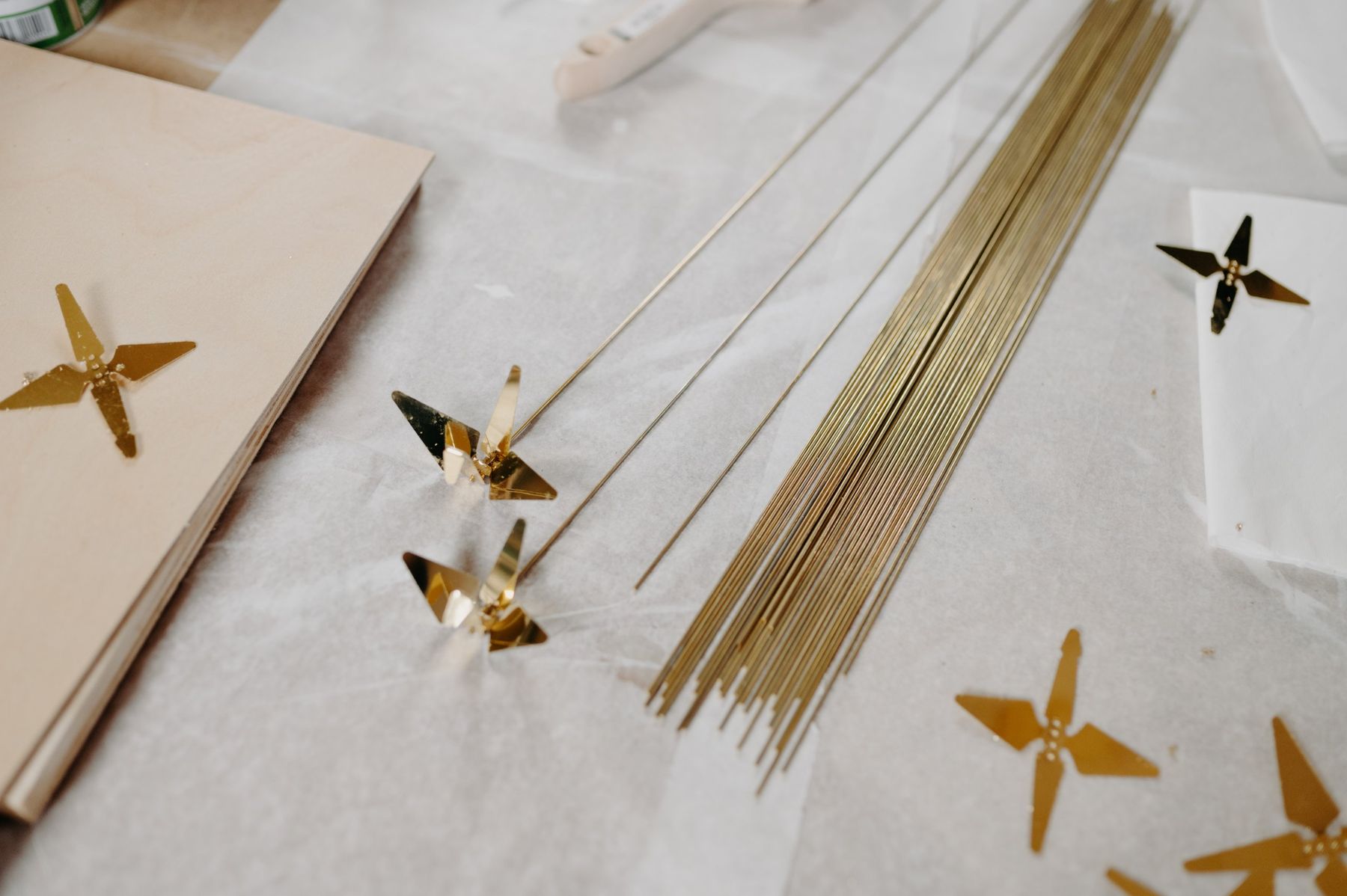Brass cranes, cut flat and shaped, next to brass rods.