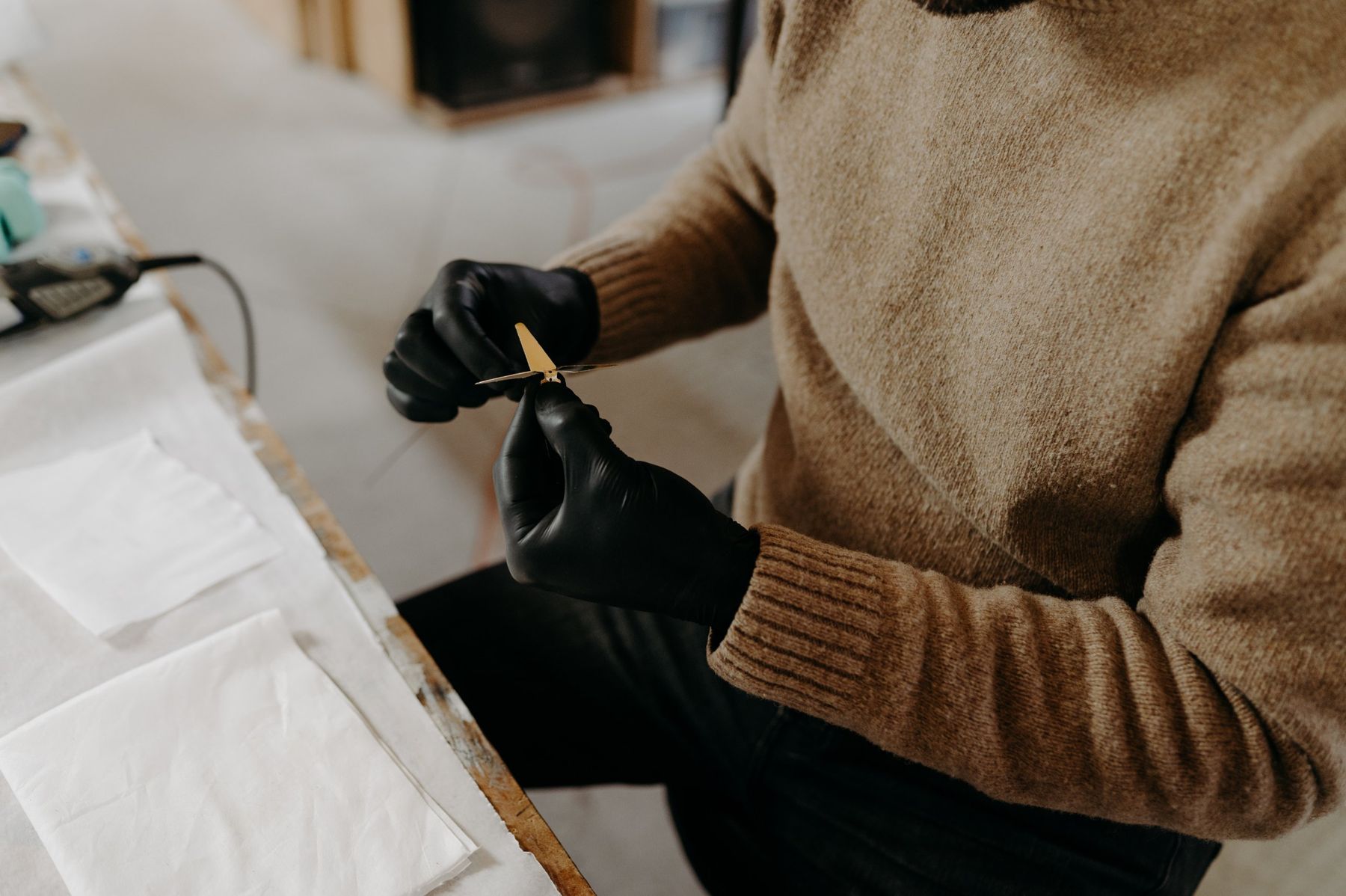 Gloved hands shaping a brass crane.