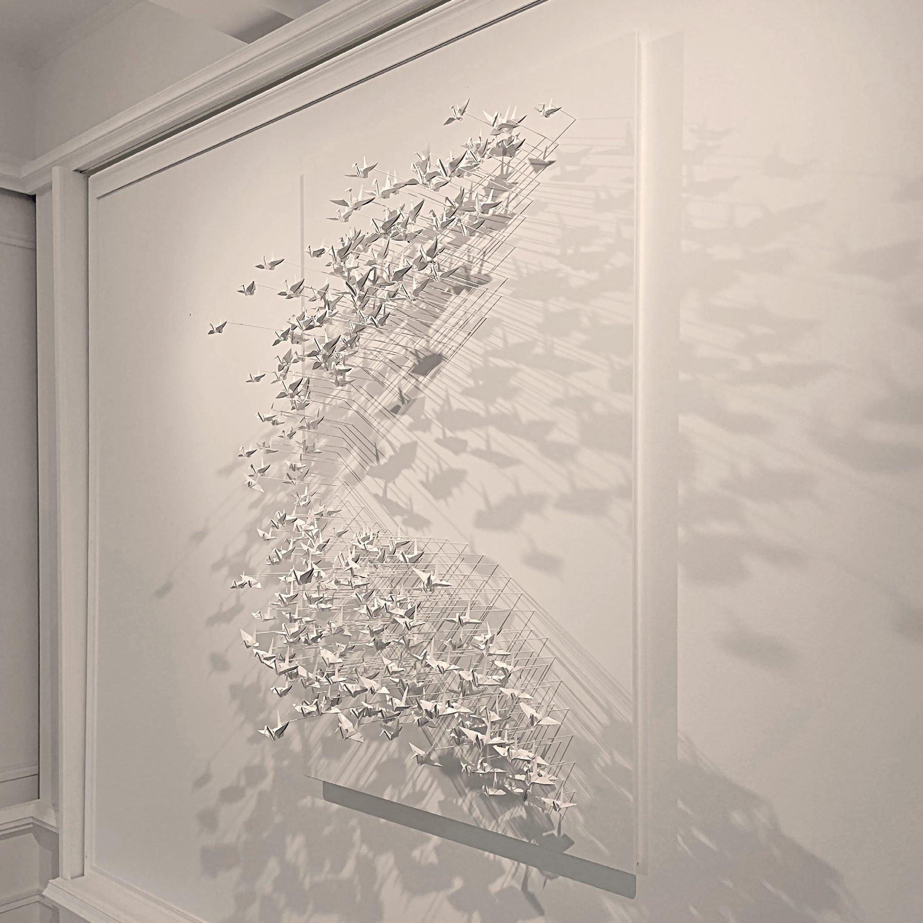 Murmuration 27, flock of white paper cranes on a panel.