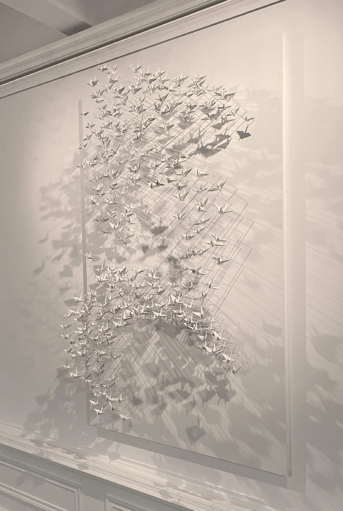 Murmuration 29, flock of white paper cranes on a panel.