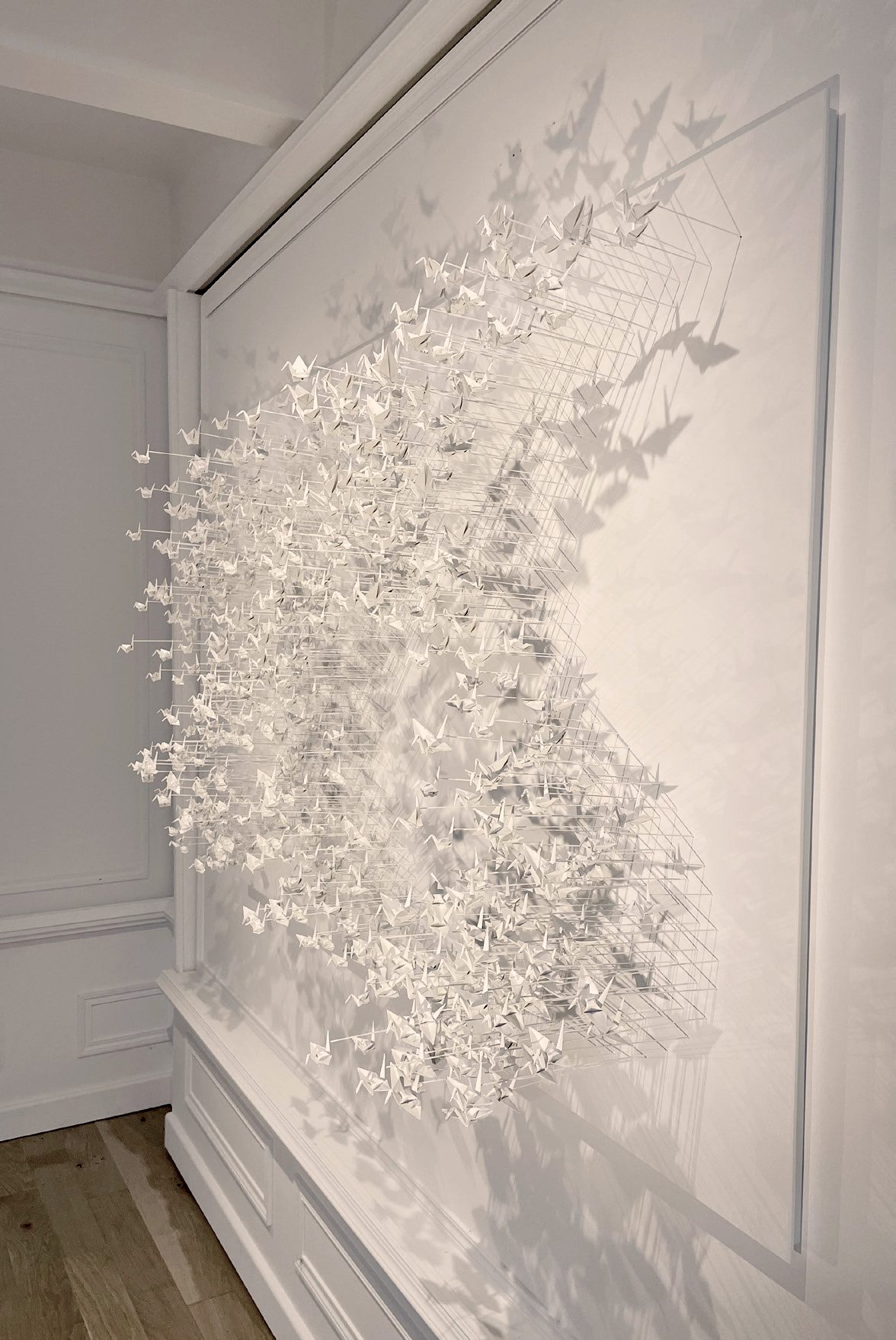 Murmuration 32, flock of white paper cranes on a panel.