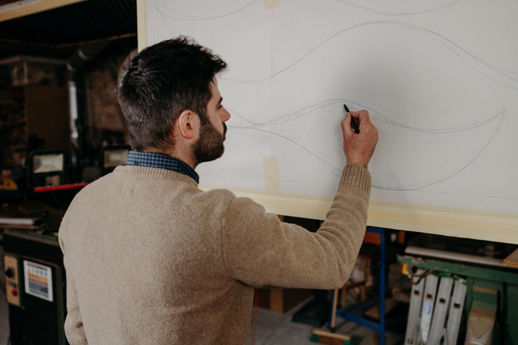 Benjamin Gaumard drawing curves in pencil on a large panel.