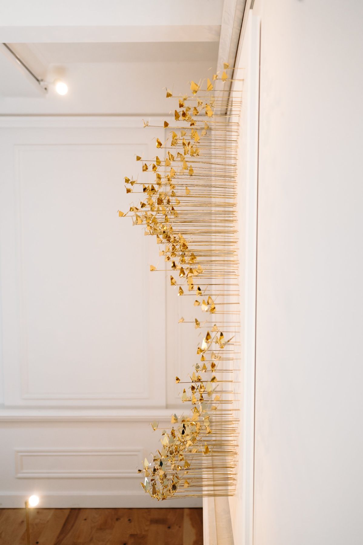 The same work seen from the side: the brass rods form a curve in relief.